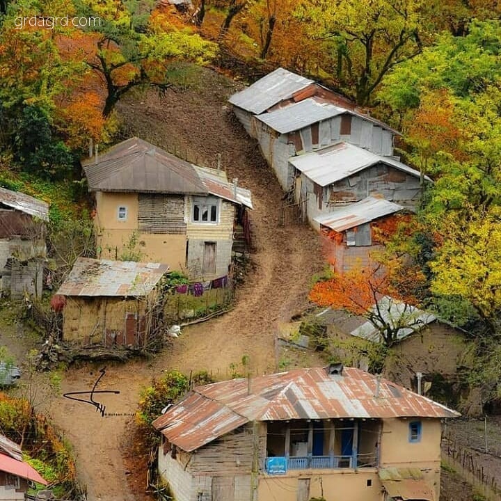 نمای هوایی از روستایی کوهستانی در شمال ایران با خانه‌های سنتی و طبیعت پاییزی رنگارنگ