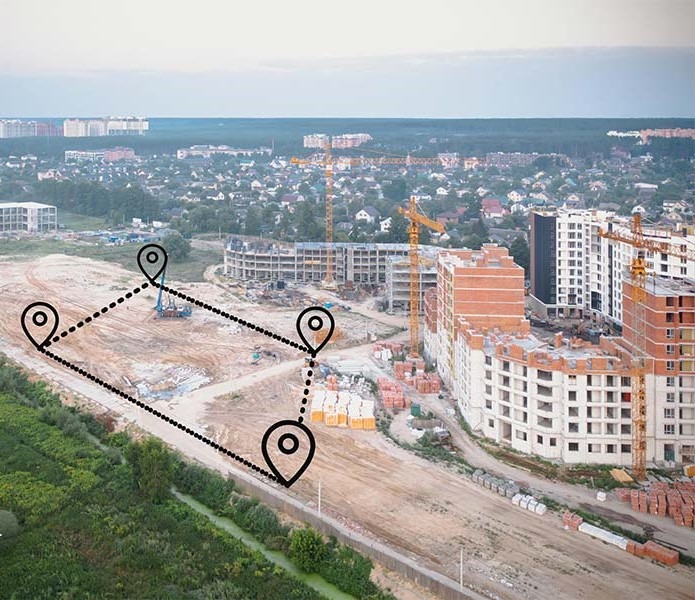 نمای هوایی از یک زمین با کاربری ساختمانی، همراه با نشانگرهای موقعیت و ساختمان‌های در حال ساخت در پس‌ زمینه
