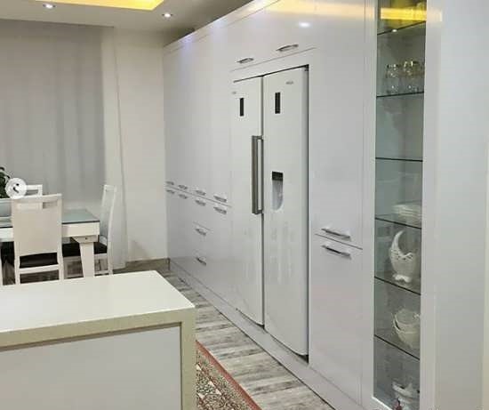 آشپزخانه مدرن سفید با کابینتهای براق و یخچال توکار