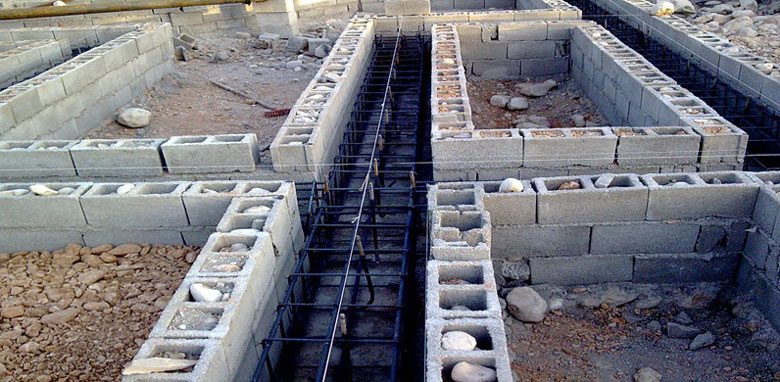 فونداسیونهای بلوک سیمانی با میلگرد در حال ساخت در یک سایت ساختمانی خاکی