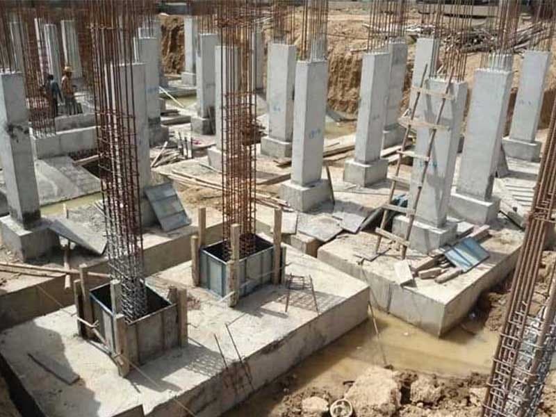 آرایهای از فونداسیونهای بتنی منفرد و قالبهای ستون با میلگردهای بیرون زده