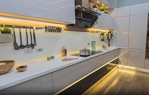 آشپزخانه مدرن با کابینتهای براق سفید و خاکستری، نورپردازی زیر کابینت و پایهکابینت
