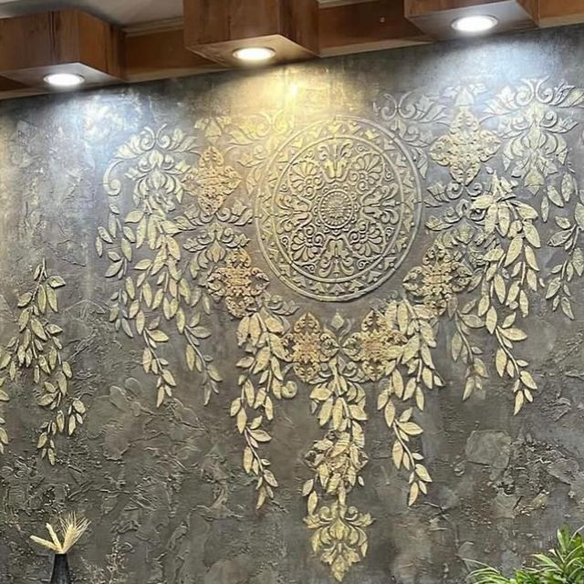 دیوار پتینه کاری شده با طرح‌های برجسته طلایی و نقوش اسلیمی و برگ، با نورپردازی مخفی