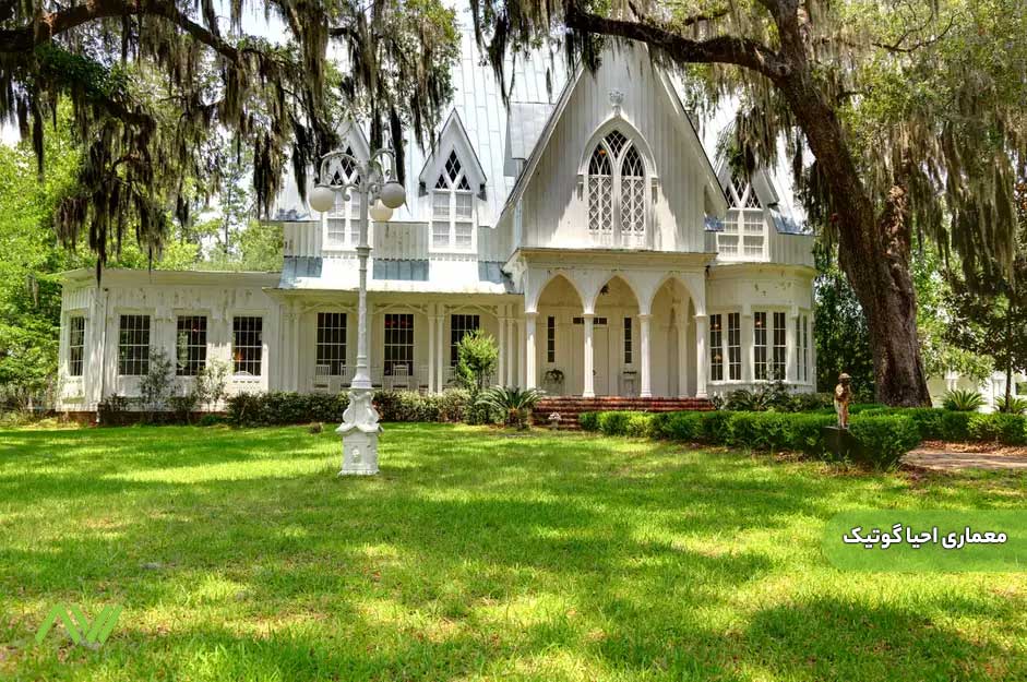 تصویری از یک خانه مسکونی بزرگ و سفید در میان فضای سبز، که عناصر سبک معماری احیا گوتیک (Gothic Revival) در آن به وضوح دیده میشود. این عناصر شامل طاقهای نوکتیز، پنجرههای کشیده با شبکهکاری ظریف و شیروانیهای تند است که به ساختمان ظاهری دراماتیک و رمانتیک بخشیدهاند