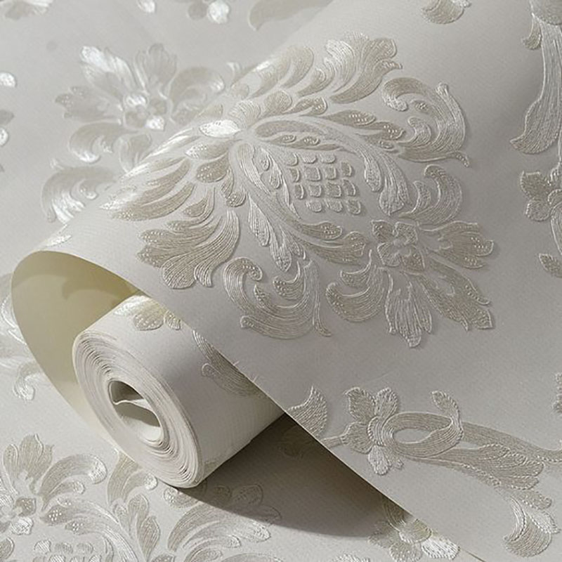 رول باز شده کاغذ دیواری با طرح برجسته (Embossed) داماسک به رنگ سفید و کرم روشن، بافت مناسب برای طراحی داخلی مدرن