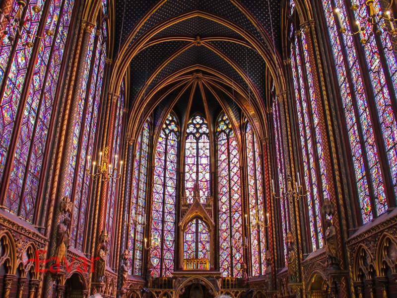 نمای داخلی کلیسای سنت-شاپل پاریس، با دیوارهای کاملاً پوشیده از شیشههای رنگی عظیم و نورپردازی رنگارنگ به سبک معماری گوتیک