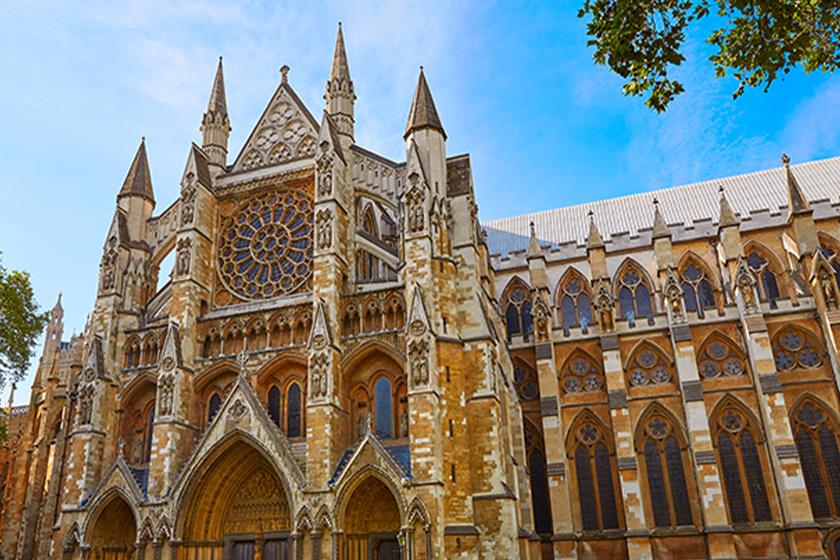 نمایی نزدیک از نمای غربی کلیسای وست مینستر لندن، با جزئیات معماری گوتیک شامل پنجره رُز بزرگ، قوسهای نوکتیز و تزیینات سنگی عمودی