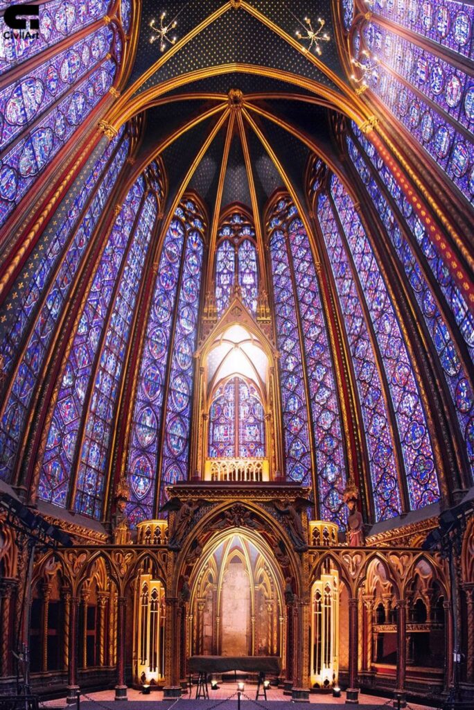 نمای داخلی کلیسای سنت-شاپل پاریس با دیوارهای شیشهای رنگی بزرگ و نورپردازی دراماتیک به سبک معماری گوتیک