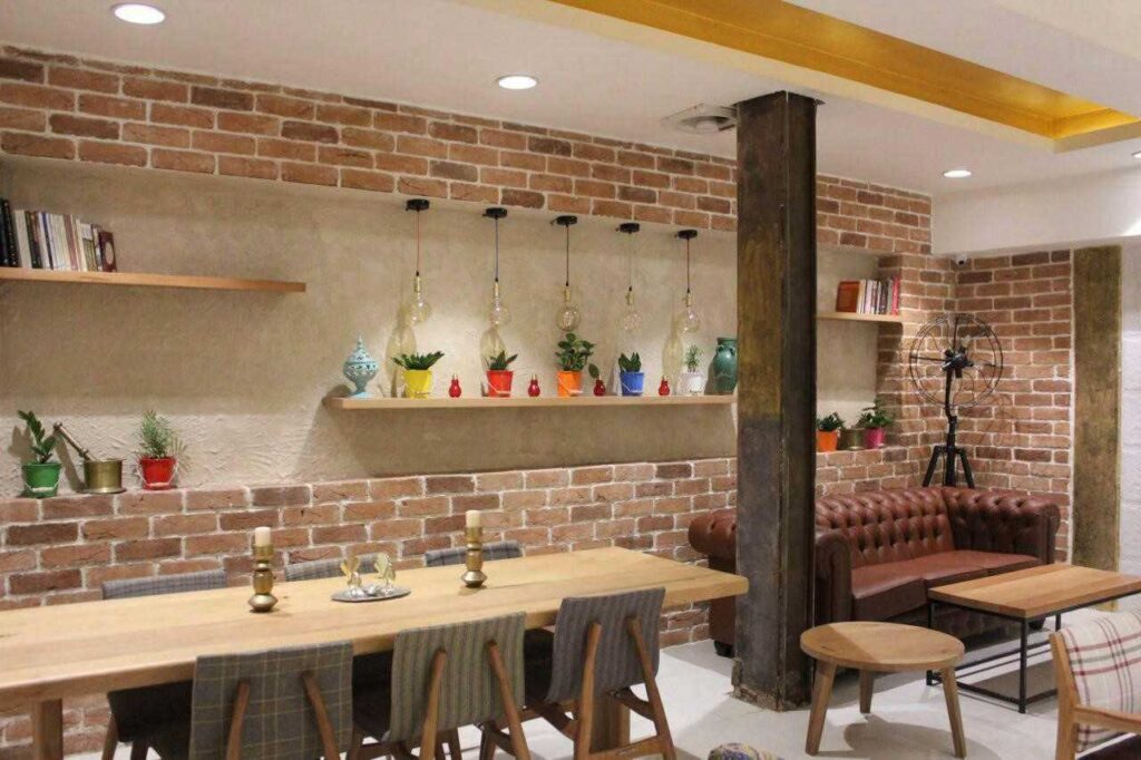دکوراسیون داخلی با آجرنما، آجرکاری دکوراتیو در پذیرایی یا کافه، میز چوبی بزرگ، کاناپه چرمی و ستون فلزی