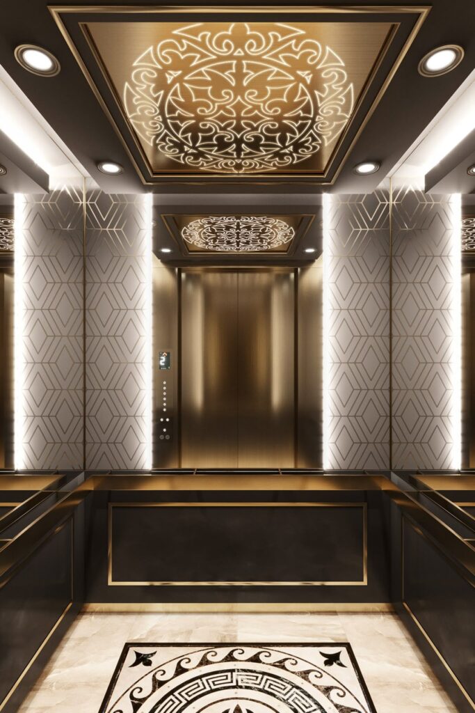 کابین آسانسور سلطنتی/نئوکلاسیک با متریال برنجی طلایی (گلد)، دیوارهای طرح‌دار هندسی، سقف فلزی حکاکی شده، و نورپردازی لوکس و متمرکز