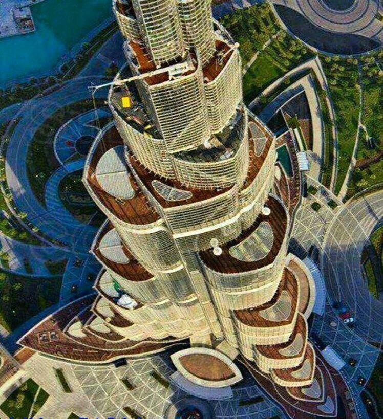 نمای نزدیک از بالای برج خلیفه که ساختار پلکانی و سه‌بخشی آن، موسوم به هسته پشت‌بند (Buttressed Core) را با جزئیات کامل و فضای سبز اطراف نمایش می‌دهد