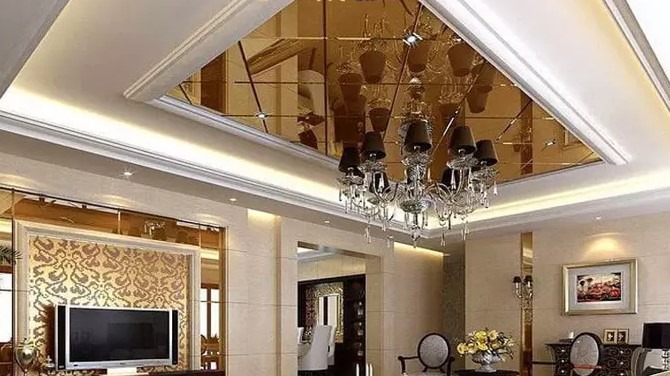 سقف کاذب مجلل با ترکیب گچ‌بری کلاسیک و پنل‌های آینه‌ای دودی/برنز با نورپردازی مخفی و لوستر کریستالی