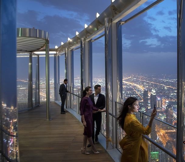 بازدیدکنندگان در حال تماشای نمای شبانه و چراغانی شهر دبی از تراس مشاهده لوکس در طبقات بالای برج خلیفه، بلندترین سازه جهان
