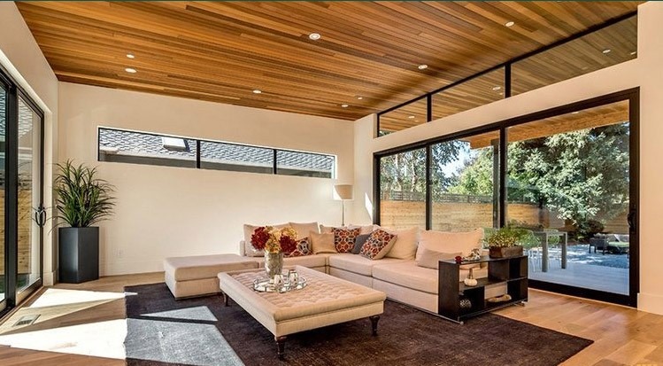 سقف چوبی لوور یا ترموود خطی در فضای نشیمن مدرن با پنجره‌های بزرگ و نورپردازی توکار