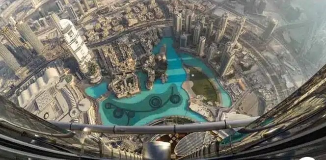 نمای دید پرنده از حوضچه فواره دبی و برج‌های اطراف که از ارتفاع بالای برج خلیفه و از داخل یک آسانسور یا شیشه مشاهده ثبت شده است