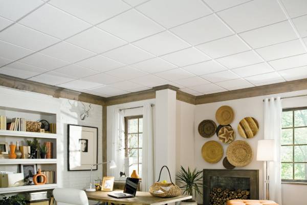 تصویری از فضای داخلی یک اتاق نشیمن یا دفتر کار خانگی با سقف کاذب آکوستیک (سقف مشبک) سفید، دیوار سفید آجری و دکوراسیون روستیک