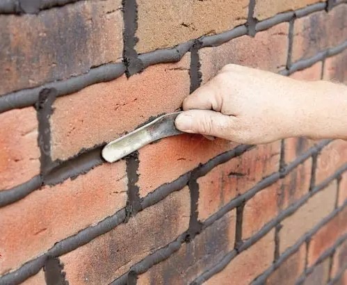 پرداخت و شکل‌دهی نهایی ملات بندکشی تیره بین آجرهای نما با استفاده از ابزار مخصوص (قلم بندکشی مقعر) برای آب‌بندی و زیبایی نهایی دیوار آجری