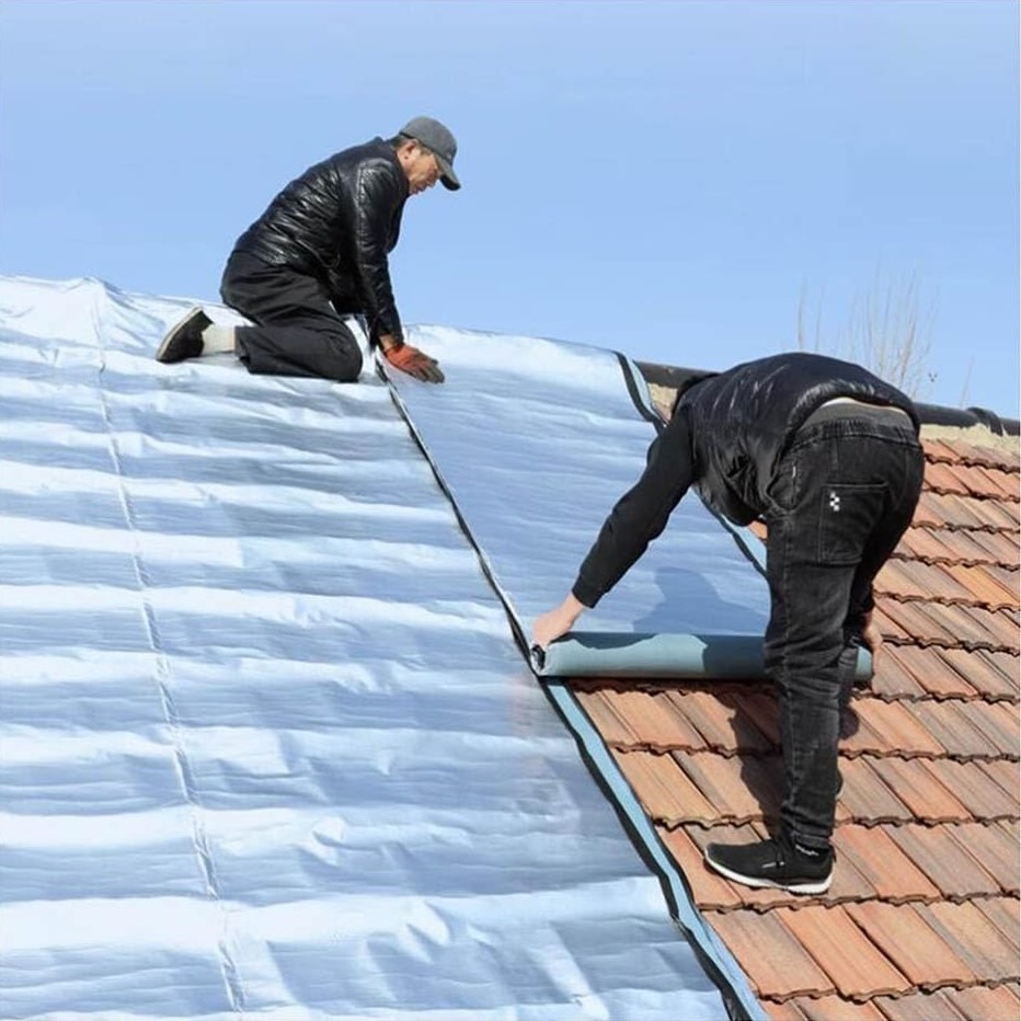 نصب عایق رطوبتی بازتابنده بر روی سقف شیبدار با پوشش سفالی توسط دو کارگر